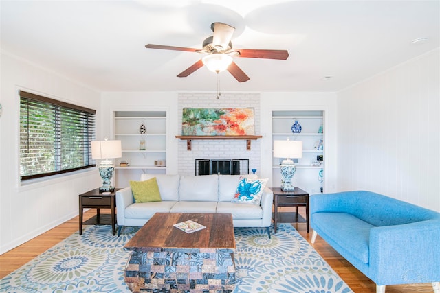 living room featuring a brick fireplace, ceiling fan, wooden walls, wood-type flooring, and built in features