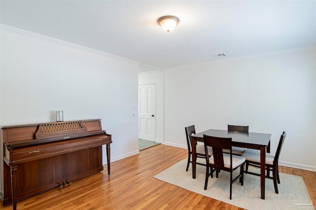 dining room featuring light wood-type flooring and crown molding