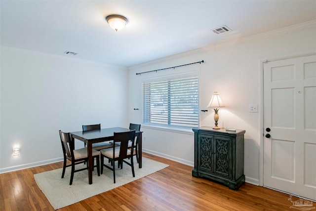 dining area with wood-type flooring and ornamental molding