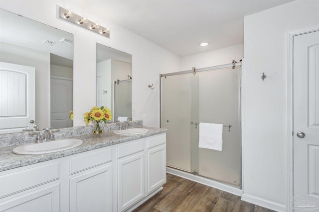 bathroom with hardwood / wood-style floors, walk in shower, and vanity