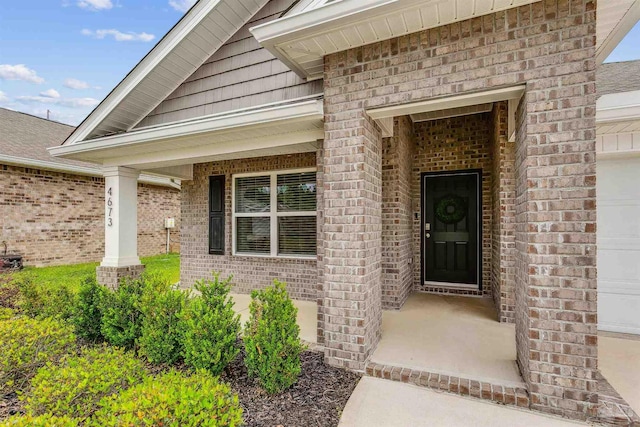 view of exterior entry featuring a garage and a porch