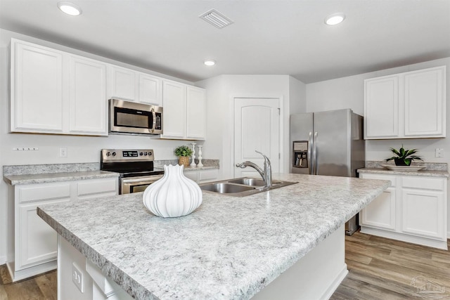 kitchen with a kitchen island with sink, appliances with stainless steel finishes, and light hardwood / wood-style flooring