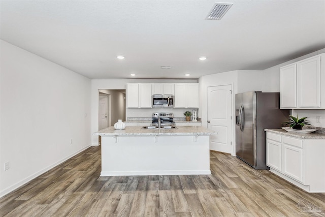 kitchen featuring an island with sink, white cabinetry, light wood-type flooring, and appliances with stainless steel finishes