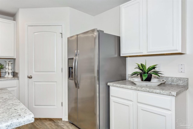 kitchen featuring white cabinets, stainless steel refrigerator with ice dispenser, and light wood-type flooring