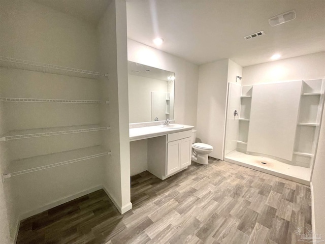 bathroom featuring vanity, wood finished floors, visible vents, a walk in shower, and toilet