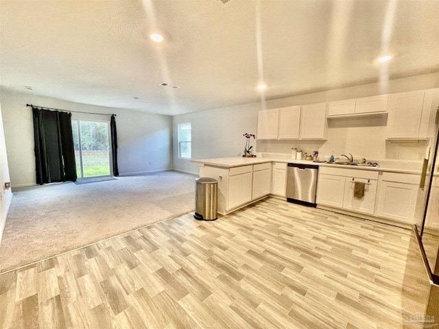 kitchen featuring open floor plan, light countertops, stainless steel dishwasher, white cabinetry, and a sink