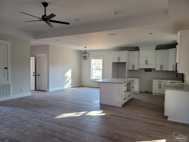 kitchen with white cabinetry, sink, a kitchen island, ceiling fan with notable chandelier, and light wood-type flooring