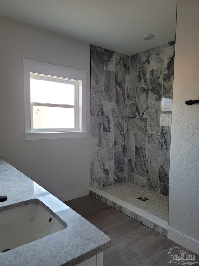 bathroom featuring a tile shower, vanity, and hardwood / wood-style flooring