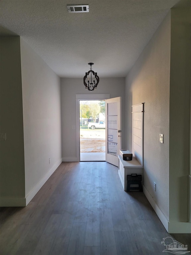 doorway featuring hardwood / wood-style floors, a textured ceiling, and an inviting chandelier