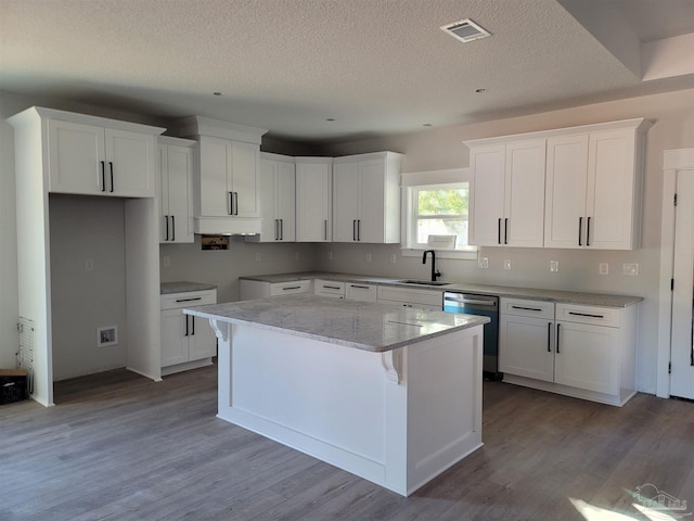 kitchen with dishwasher, a center island, white cabinets, sink, and light stone countertops