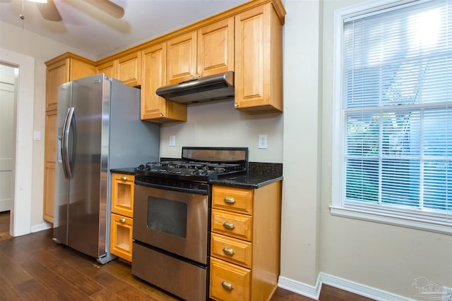 kitchen with dark hardwood / wood-style floors, dark stone counters, ceiling fan, and appliances with stainless steel finishes