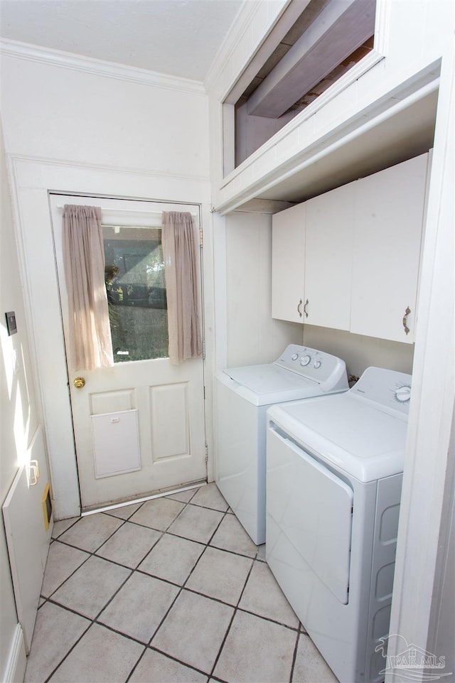 clothes washing area with cabinets, ornamental molding, washer and dryer, and light tile patterned flooring