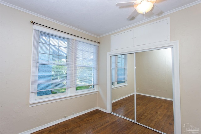 unfurnished bedroom featuring crown molding, dark wood-type flooring, ceiling fan, and a closet