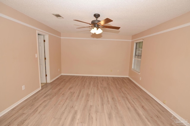 spare room featuring a ceiling fan, light wood-style flooring, visible vents, and a textured ceiling
