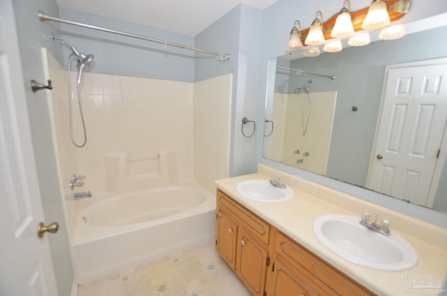 full bath with shower / bath combination, a sink, a textured ceiling, and double vanity