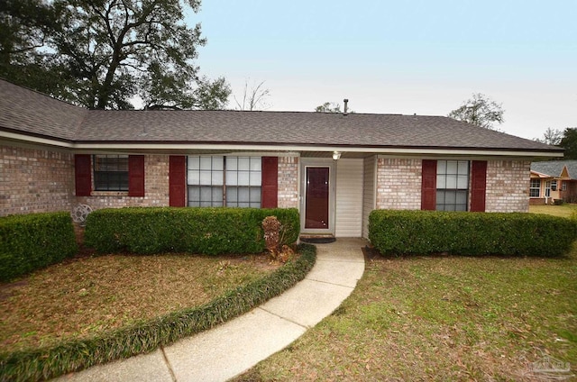 ranch-style house featuring a front yard, brick siding, and roof with shingles