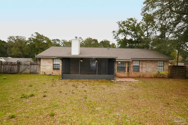 back of house featuring a fenced backyard, a sunroom, a lawn, a gate, and a chimney