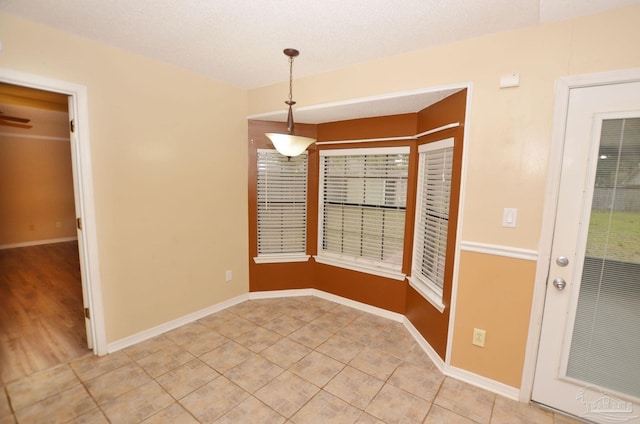 unfurnished room with light tile patterned floors, a textured ceiling, and baseboards
