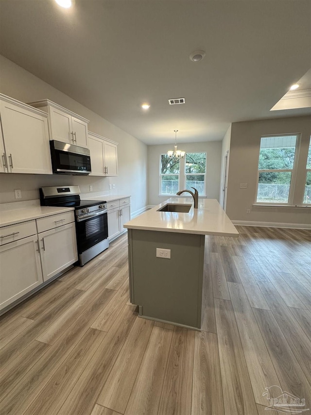 kitchen featuring sink, appliances with stainless steel finishes, a kitchen island with sink, white cabinetry, and light hardwood / wood-style floors