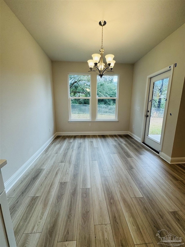 unfurnished dining area featuring a notable chandelier and light hardwood / wood-style floors