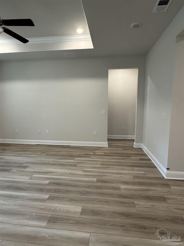 unfurnished room with a tray ceiling, light hardwood / wood-style floors, and ceiling fan