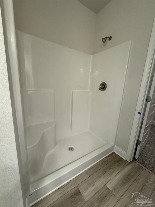 bathroom with hardwood / wood-style flooring and walk in shower