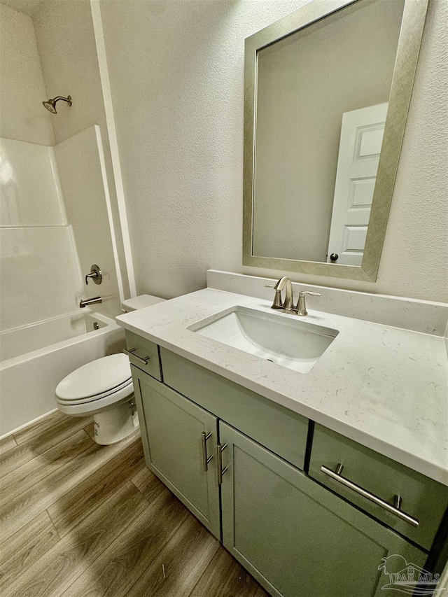 full bathroom with hardwood / wood-style flooring, shower / bathtub combination, vanity, and toilet