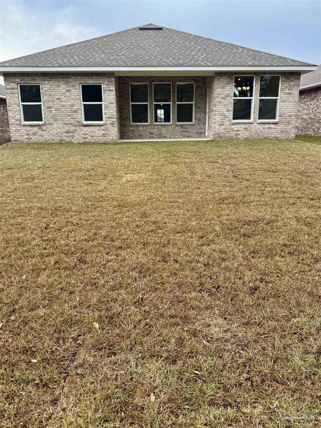 rear view of property featuring a lawn