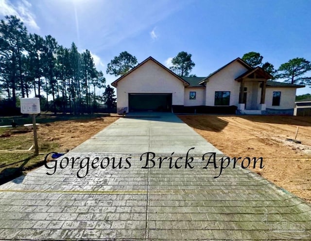 view of front of house featuring a garage, concrete driveway, and stucco siding