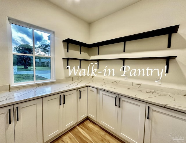 kitchen featuring light stone countertops, white cabinetry, light wood-style flooring, and open shelves