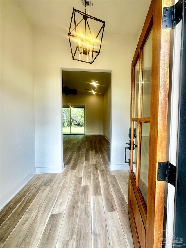 unfurnished dining area featuring a chandelier, baseboards, and wood finished floors