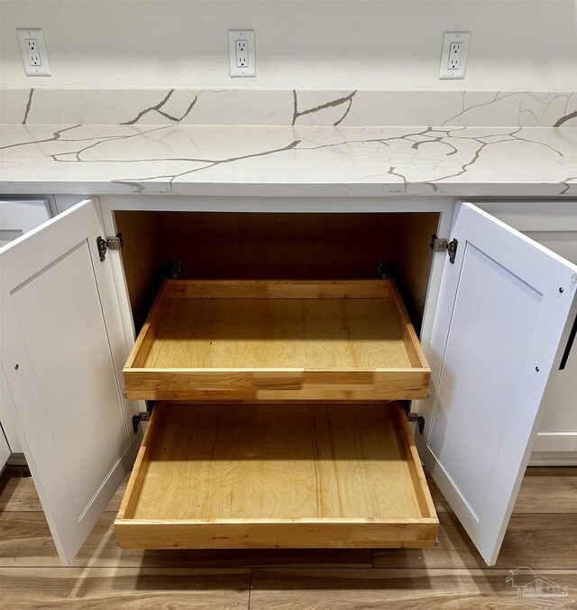 interior details with light stone counters, white cabinets, and light wood-style flooring