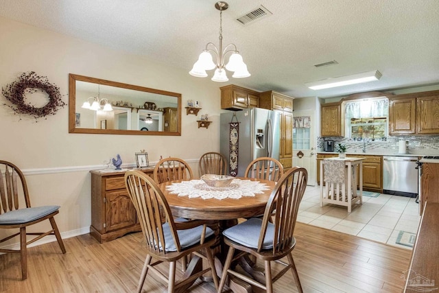 6028 Laurelwood Dr, Milton, FL 32570 - dining room with a chandelier, a textured ceiling, and light wood-type flooring
