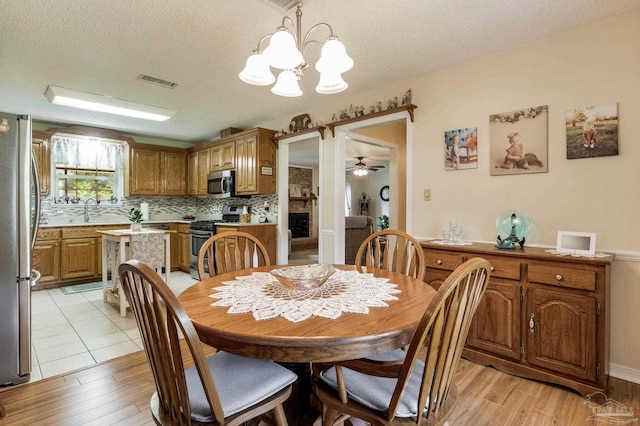6028 Laurelwood Dr, Milton, FL 32570 - dining room featuring a chandelier, a textured ceiling, light wood-style flooring, and a ceiling fan