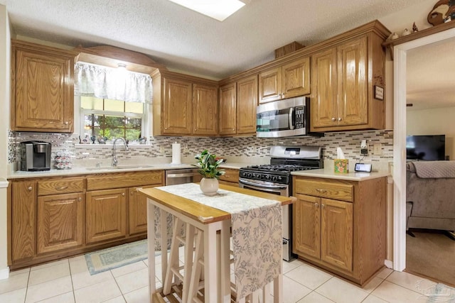 6028 Laurelwood Dr, Milton, FL 32570 - kitchen featuring appliances with stainless steel finishes, a sink, light countertops, light tile patterned floors, and a textured ceiling