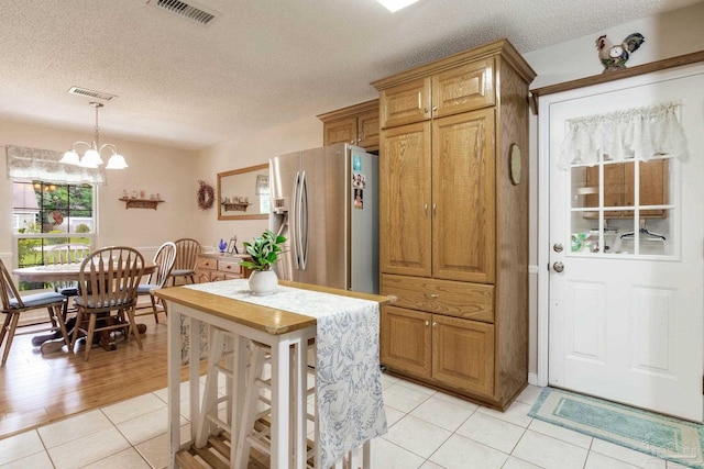 6028 Laurelwood Dr, Milton, FL 32570 - kitchen with stainless steel fridge, light tile patterned floors, a textured ceiling, a chandelier, and pendant lighting