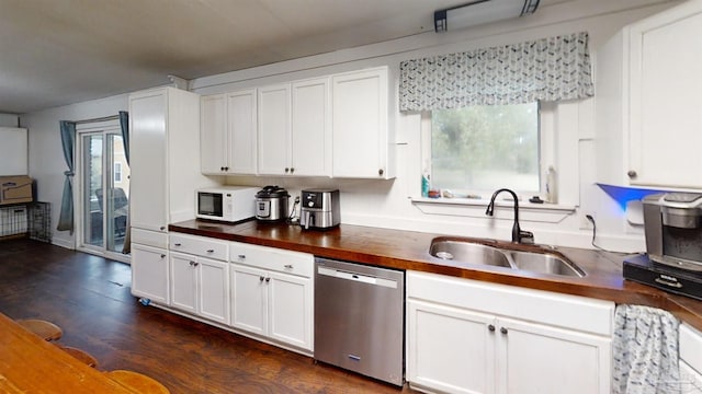 kitchen with white microwave, butcher block countertops, a sink, white cabinets, and dishwasher