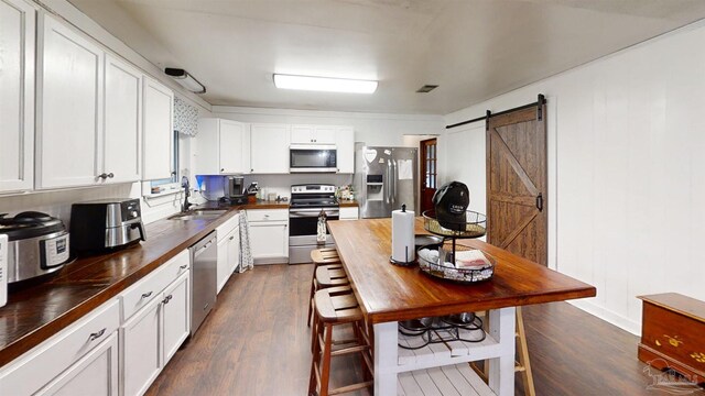 kitchen featuring butcher block counters, appliances with stainless steel finishes, a sink, and a barn door