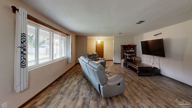 living area with baseboards, a textured ceiling, visible vents, and wood finished floors