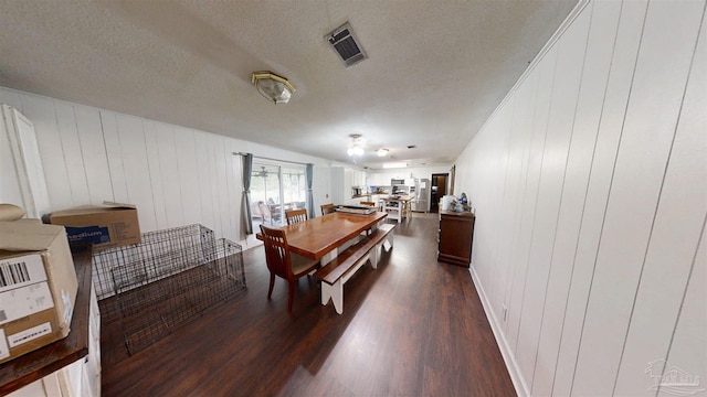 dining space featuring a textured ceiling, dark wood-style flooring, and visible vents