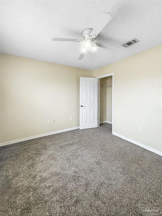 empty room with dark colored carpet, a textured ceiling, and ceiling fan