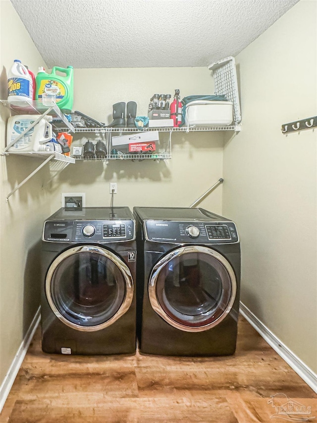 clothes washing area featuring washer and dryer, wood-type flooring, and a textured ceiling