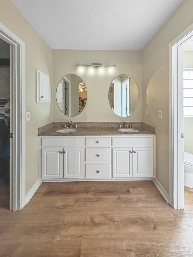 bathroom with hardwood / wood-style flooring, vanity, toilet, and a textured ceiling