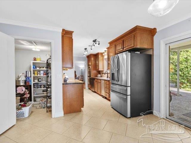 kitchen with appliances with stainless steel finishes, sink, light tile patterned floors, crown molding, and track lighting