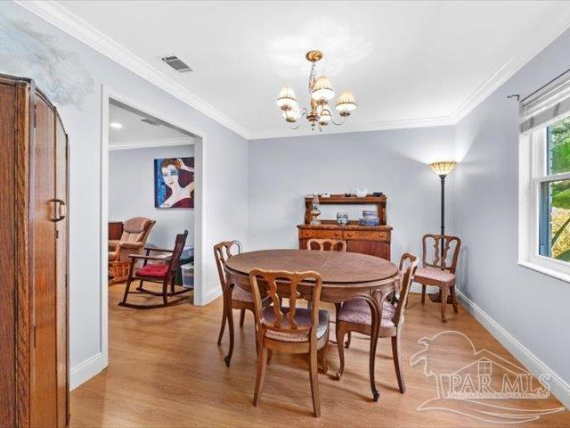 dining area with ornamental molding, a chandelier, and light wood-type flooring