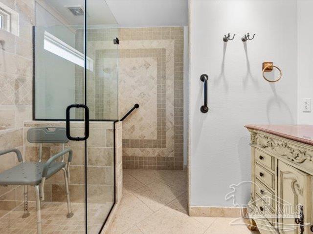 bathroom with tile patterned flooring, vanity, and walk in shower