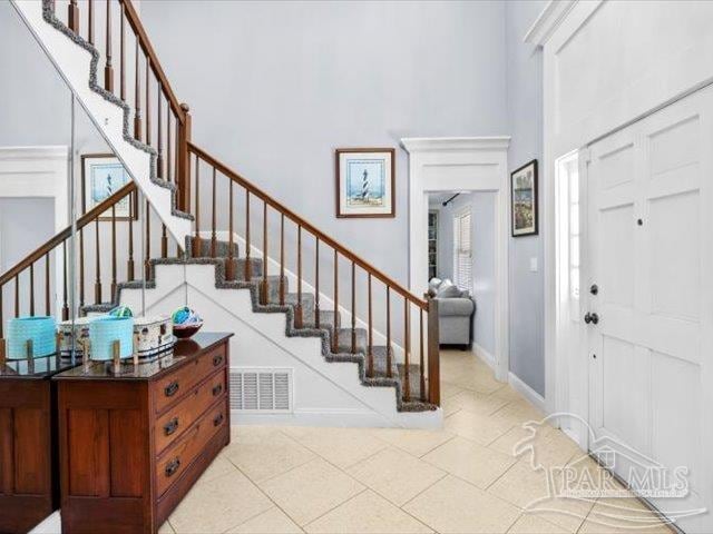 entryway featuring a high ceiling and light tile patterned flooring