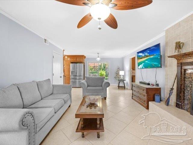 living room with ornamental molding, light tile patterned floors, and ceiling fan