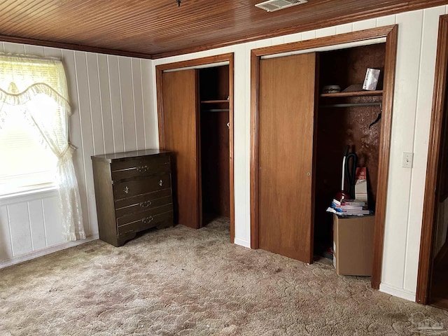 unfurnished bedroom featuring multiple closets, light carpet, and wood ceiling