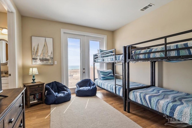 bedroom with access to exterior, french doors, visible vents, and wood finished floors